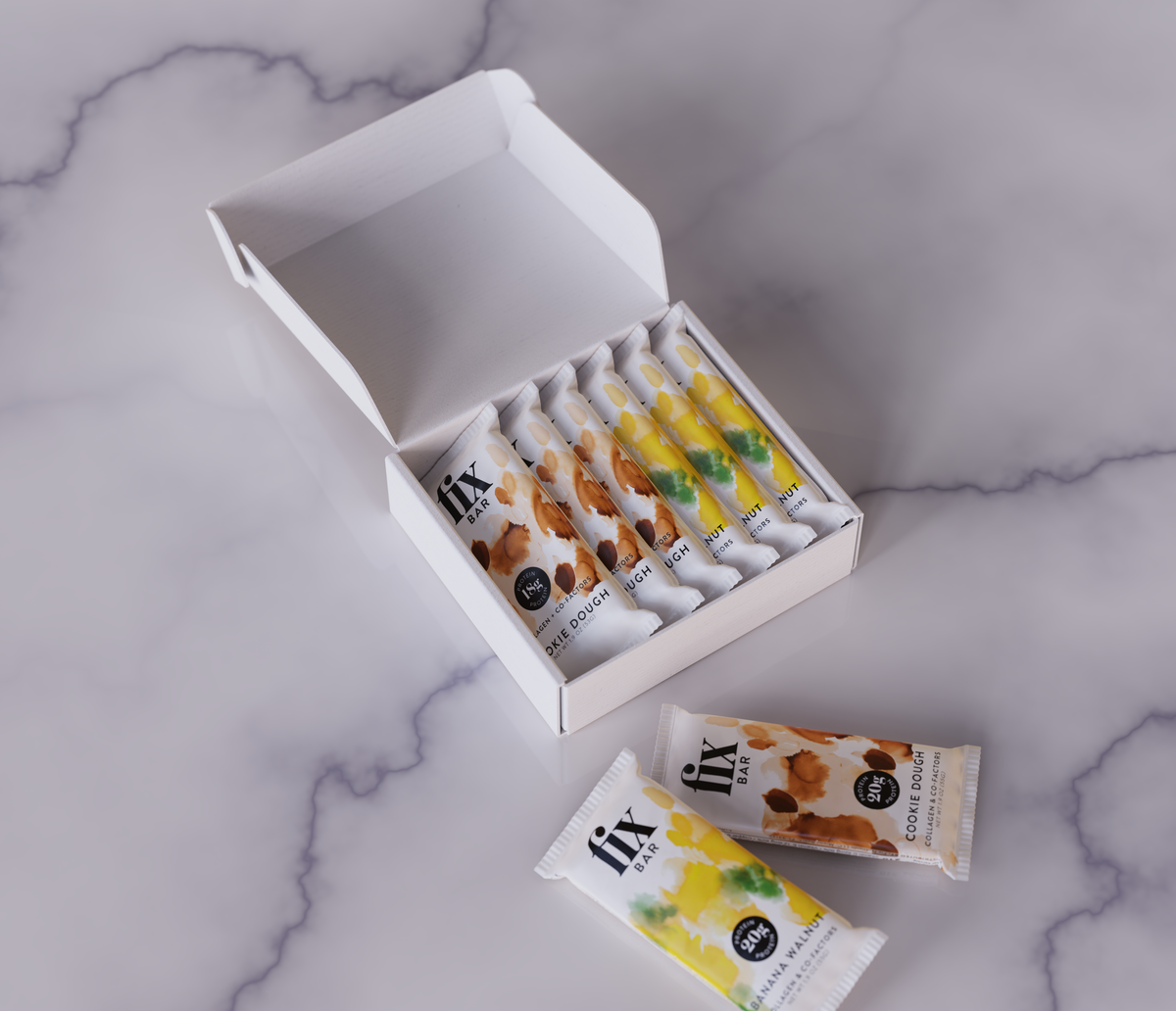 An open white box containing several Fix Bars, with two loose bars placed in front, photographed on a light marble surface. 